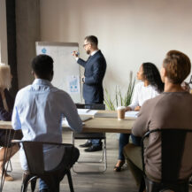 Boss,Stands,Near,Flip,Chart,Presents,Topic,To,Audience,,Demonstrate